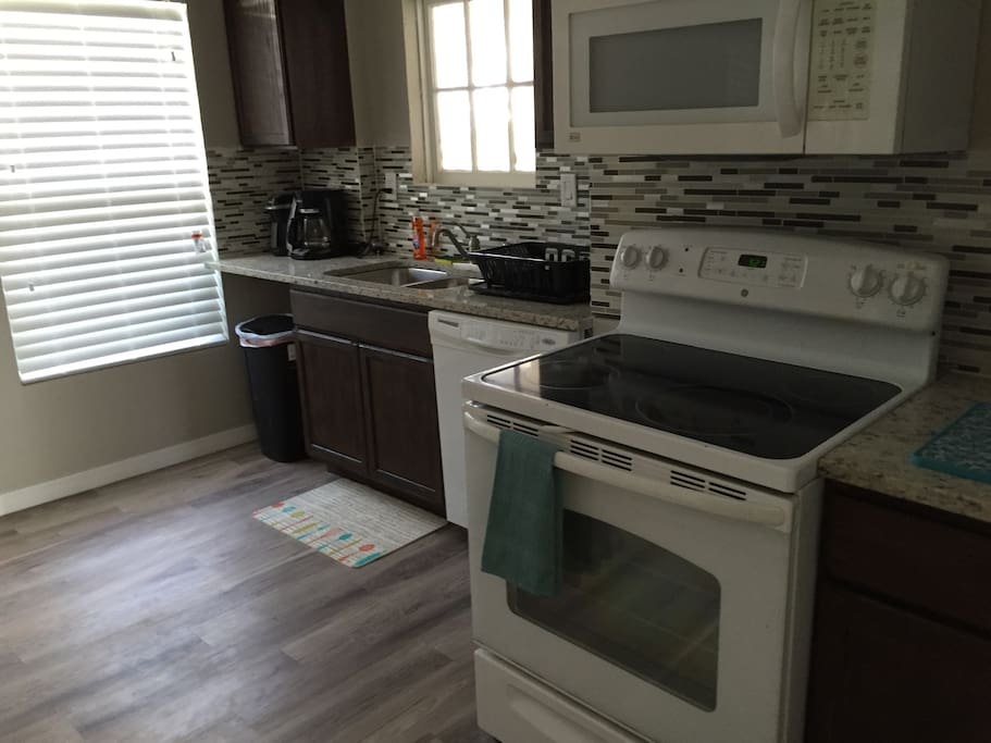 Fully stocked kitchen with coffee maker, kuerig machine, toaster, pots and pans, and cutlery