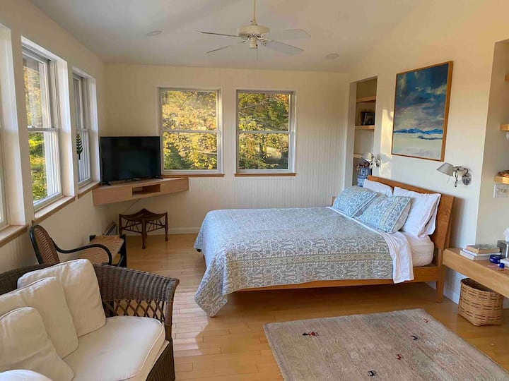 The main bedroom extends across the entire southern side of the house.  There are 10 windows, with an extraordinary view of the mountains.  The bed is a queen size bed.  There is a flat screen television, a sofa and large sturdy desk facing south. 