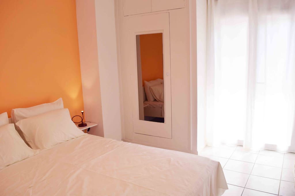 view of the sunny bedroom with a closet and a mirror