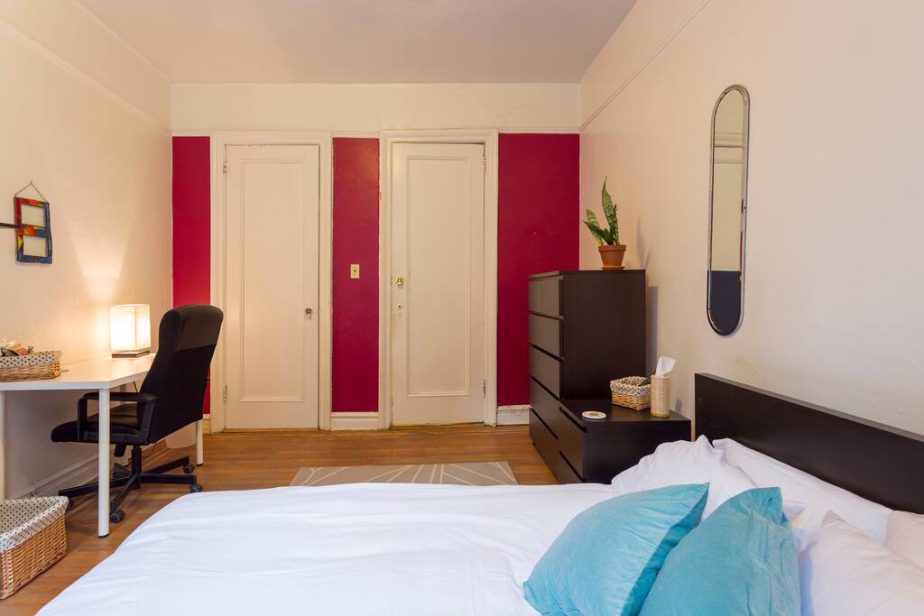 Access to closet with hangers and desk with lamp.