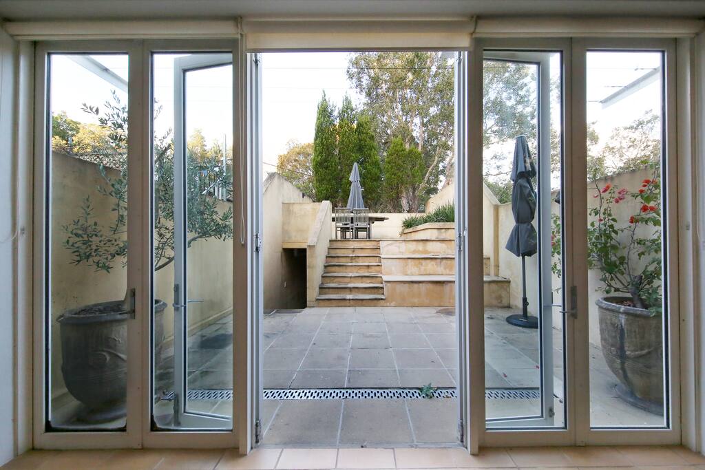 Outdoor area off the main living room with entertaining area (outdoor table and bbq). Entrance to private parking spot is located on the left, and accessible the back street.