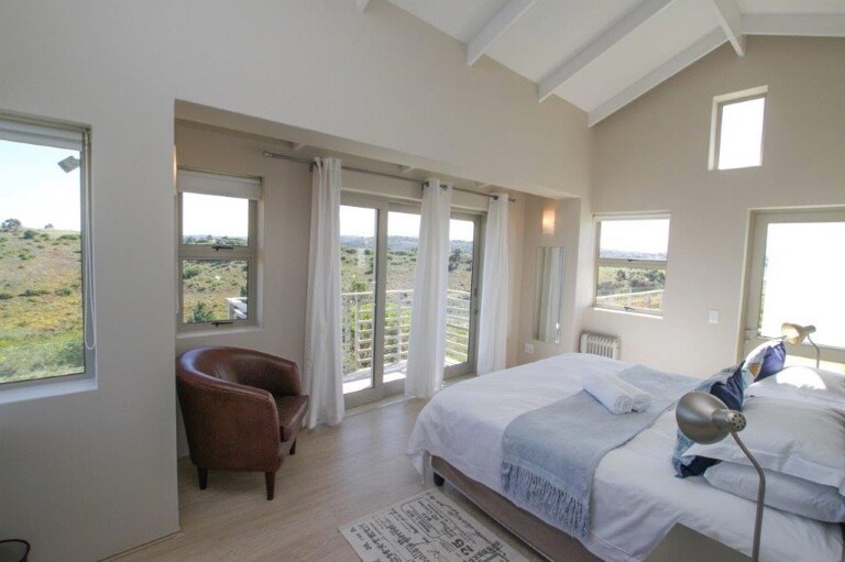 מיטה ראשית עם מרפסת פרטית ודלת לגינה ולאזור הבריכה. 