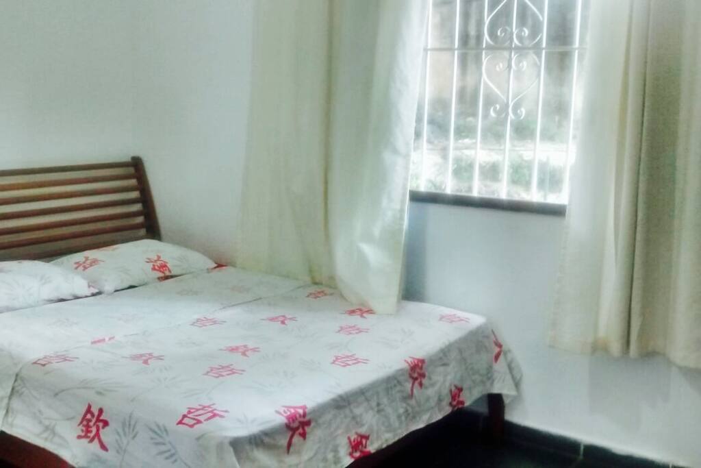 Quarto com grande cama de casal e janela com vista para o Cristo