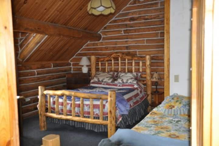 This west facing bedroom has a queen bed, with a single bed, love seat and table. One of the best Sawtooth view is from this bedroom