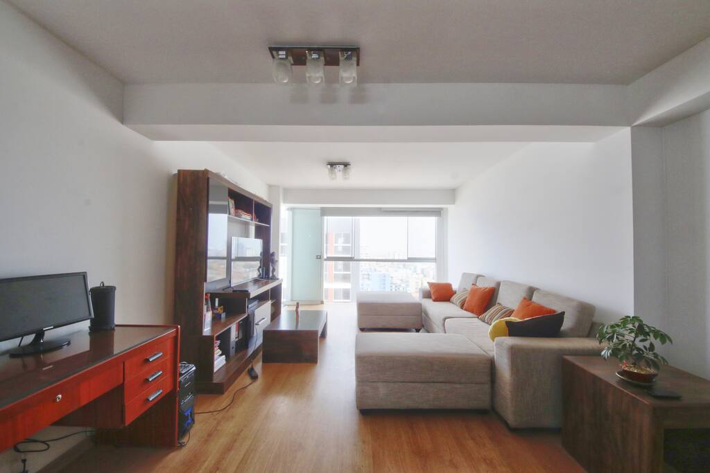 Living room with TV and a wide, three-pieces sofa