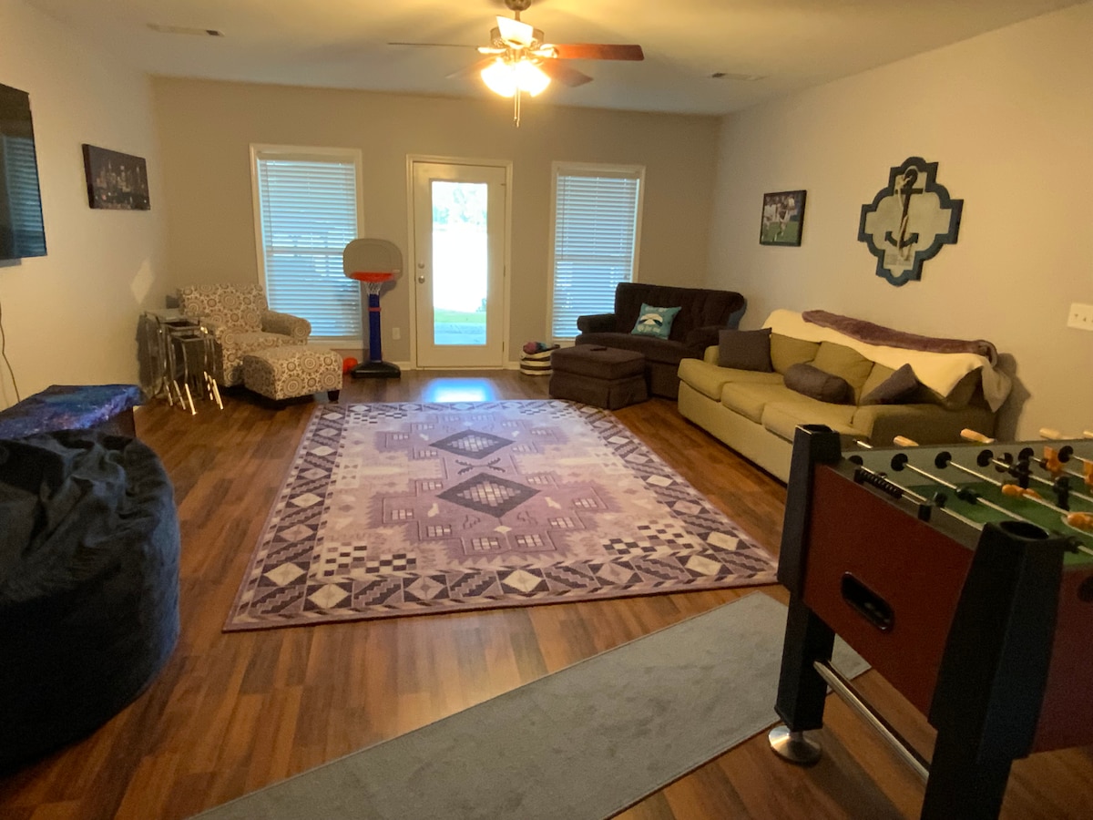 Rodinná izba na prízemí s futbalovým stolom, veľkou pohodlnou rozkladacou pohovkou a televízorom. Hry v truhle pod televízorom vedľa obrovskej stoličky so sedacím vakom