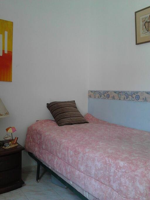 Habitación para 2 personas con cama sencilla y cama nido, cuenta con aire acondicionado y ventilador de piso.