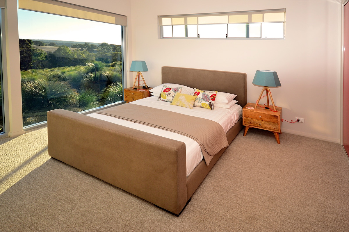 Spacious light-filled bedroom with queen size bed and valley views