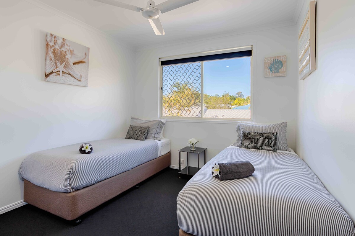 חדר שינה זוגי עם טלוויזיה, תחנת משחקים, מזגן ומאוורר תקרה.