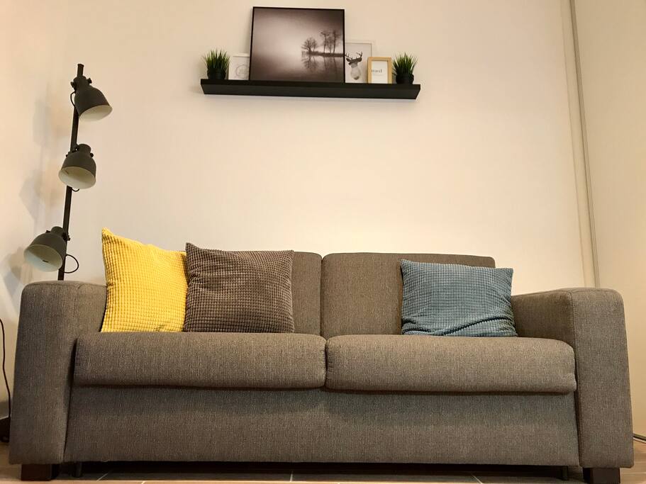 Living room with carefully chosen details like industrial lamp, soft and colorful pillows and modern photography