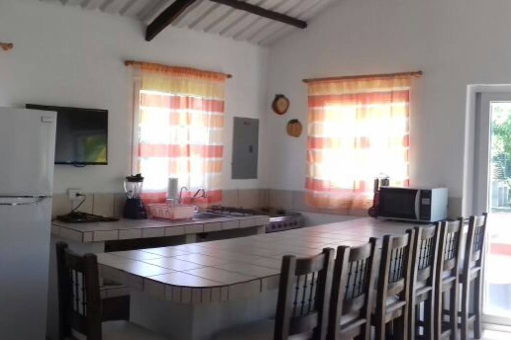 Cocina con refrigerador, congelador, estufa, vajilla, microondas.