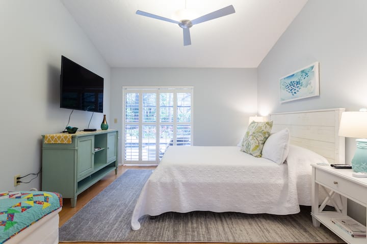 חדר שינה ראשי עם דלתות הזזה מזכוכית שנפתחות לבריכה.