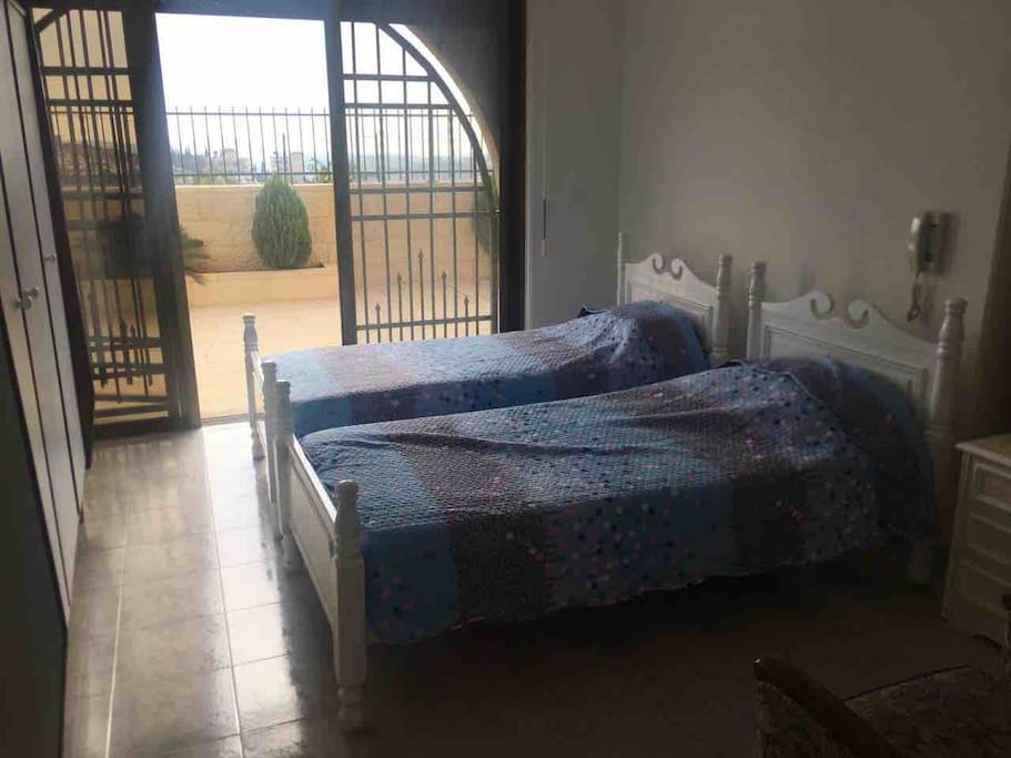 Bedroom with two single beds and a hard mattress available behind closet.