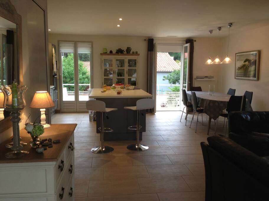 Etage : grande espace de vie (salon, cuisine avec îlot central) donnant sur balcon avec vue sur la piscine et les montagnes