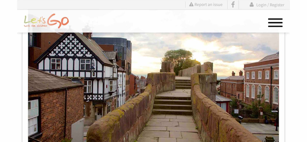 An elevated view showcases a historic stone walkway lined with aged buildings, featuring a mix of architectural styles. The walkway leads toward a serene horizon with soft clouds illuminated by warm light, creating a calm atmosphere.