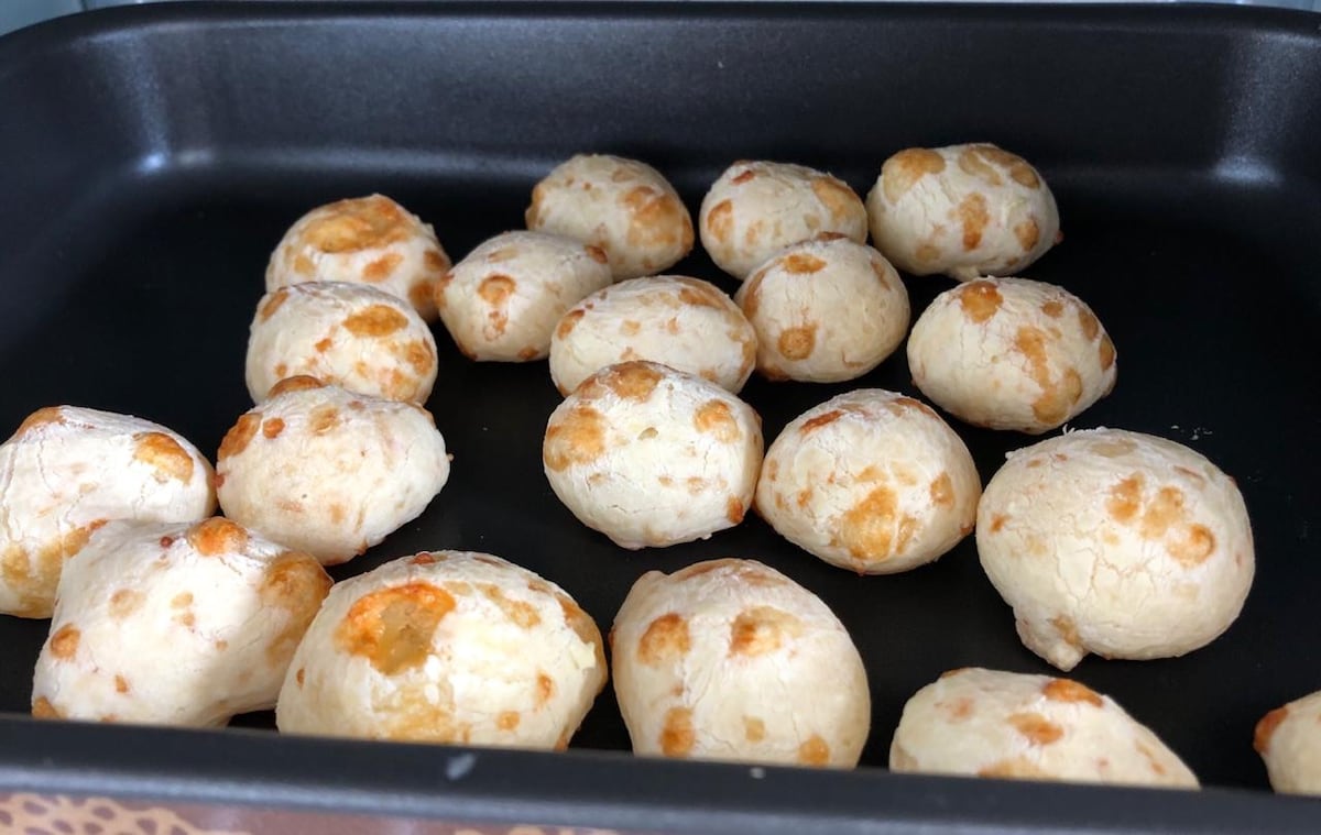 A tray displays freshly baked round bread rolls with a golden-brown crust. Each roll showcases a slightly cracked surface, revealing a soft and airy interior. The arrangement is neat, highlighting the inviting nature of the warm baked goods.