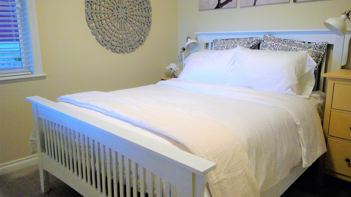 Брачна спална соба на пониското ниво со поглед на езерото и поплочениот двор. 