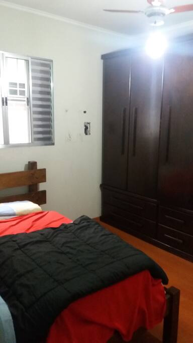 Quarto: cama de solteiro + colchão no chão, ventilador de teto, armário e gavetas.