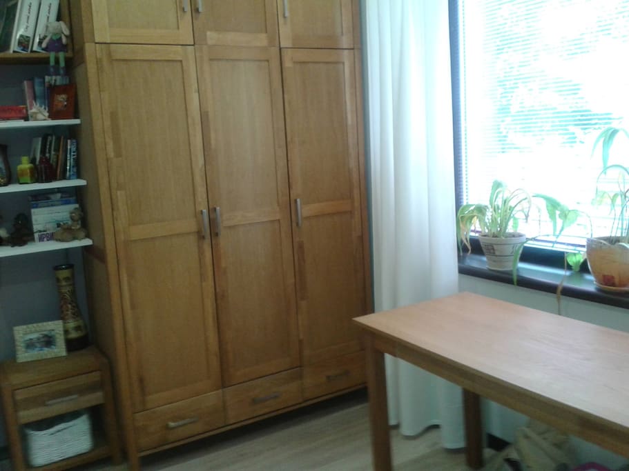 Большой шкаф для одежды и письменный стол у окна
