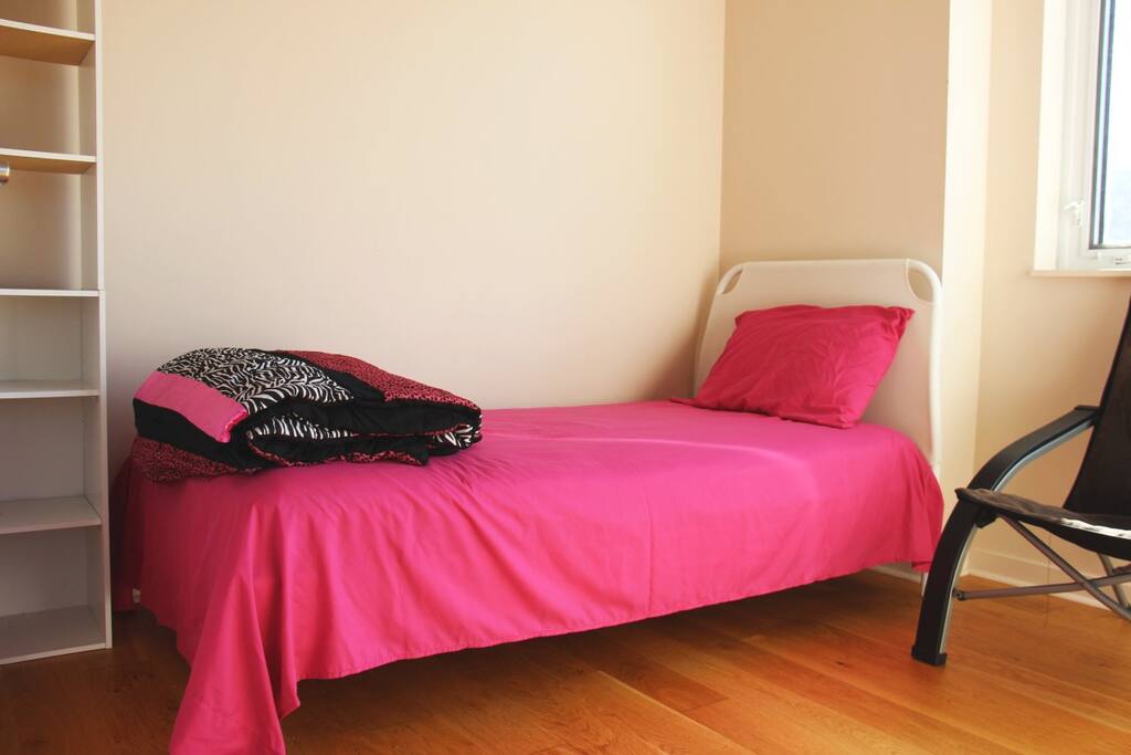 Room #2 in our apartment: Single bed, shelves, comfy chair, and a closet.