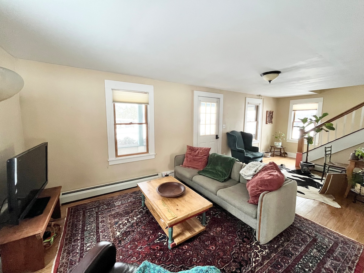 Sala de estar soleada y acogedora.  El sofá es muy cómodo y podría servir como cama para huéspedes adicionales.  La mesa de centro se puede mover para dejar espacio para un colchón de aire.  Las ventanas dan al histórico County Fairgrounds ubicado al otro lado de la calle.