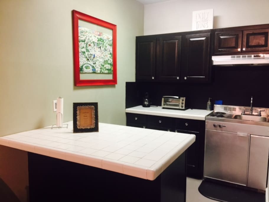 Kitchenette with dining bar, small refrigerator, Double stove top burners, and vintage poster of Atlanta