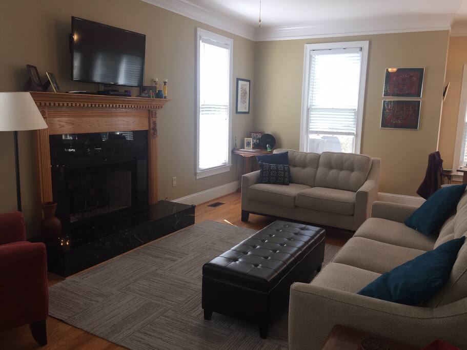 Living room with 2 couches, comfortable chair, and mounted TV with cable and netflix.