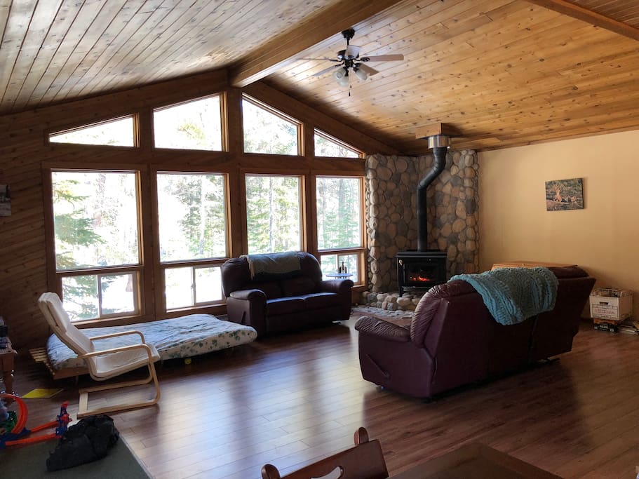 Main Livingroom/family room with sofa, love seat, futon, wood fireplace & small vintage tv. Open concept vaulted ceiling, makes for a beautiful room.