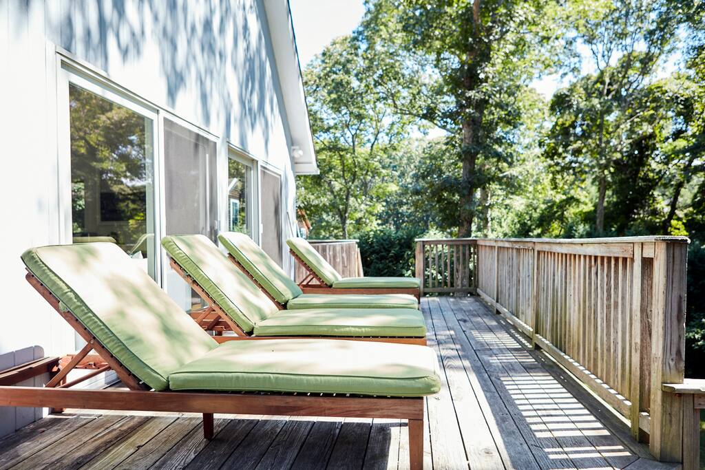 back deck on a sunny morning overlooking lawn and private woods. 4 lounge chairs. property gets lots of sunlight. new umbrella (not pictured) for this area as well.