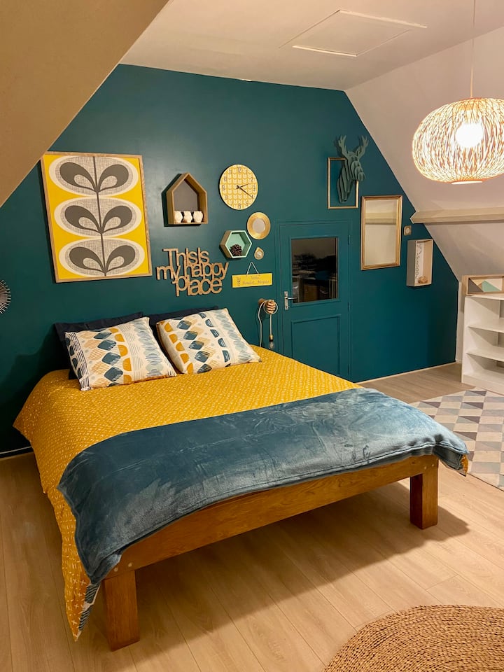 La première chambre avec son grand lit dans des tons jaunes et bleus