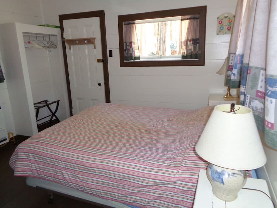 The front door opens into the sleeping area that has a queen bed, dresser and two night stands.