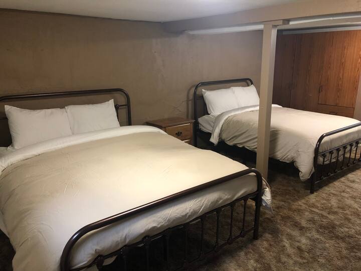 Basement bedroom with queen and full beds.  Tall dresser and wardrobe.
