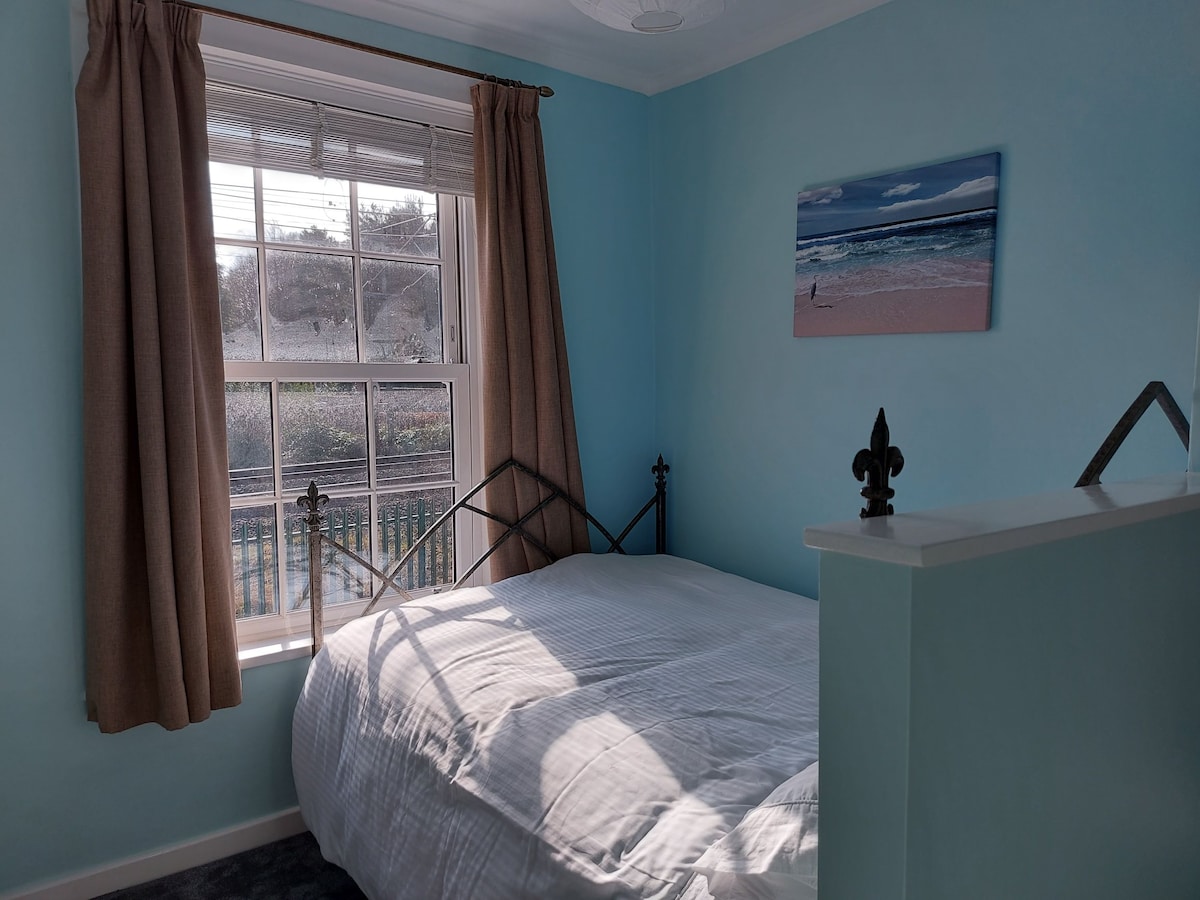 Dormitorio principal con cama matrimonial, armario, estantes y un tocador con taburete