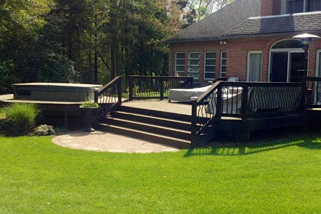 Peaceful deck and back yard... with BBQ and hot tub. Behind this area is the woods with trails, fire pit, etc.
