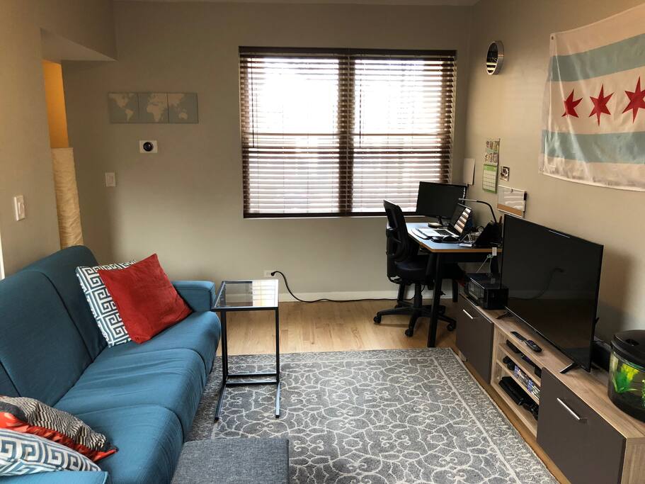 Living room with entertainment center, work desk, and a pleasant outdoor view.