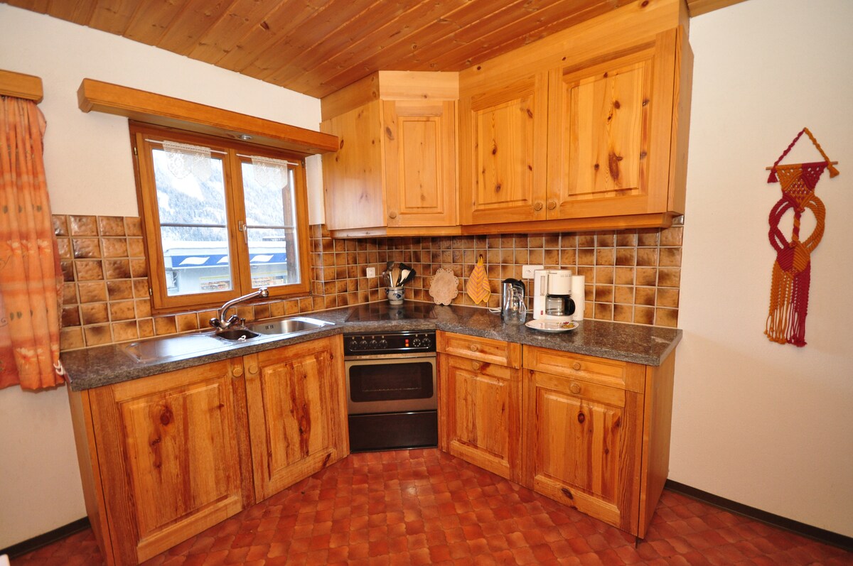 The kitchen features wooden cabinetry with a warm finish and a granite countertop. A window allows natural light to illuminate the space. Essential appliances, including a microwave and coffee maker, are present, alongside a tiled backsplash that adds texture to the area.