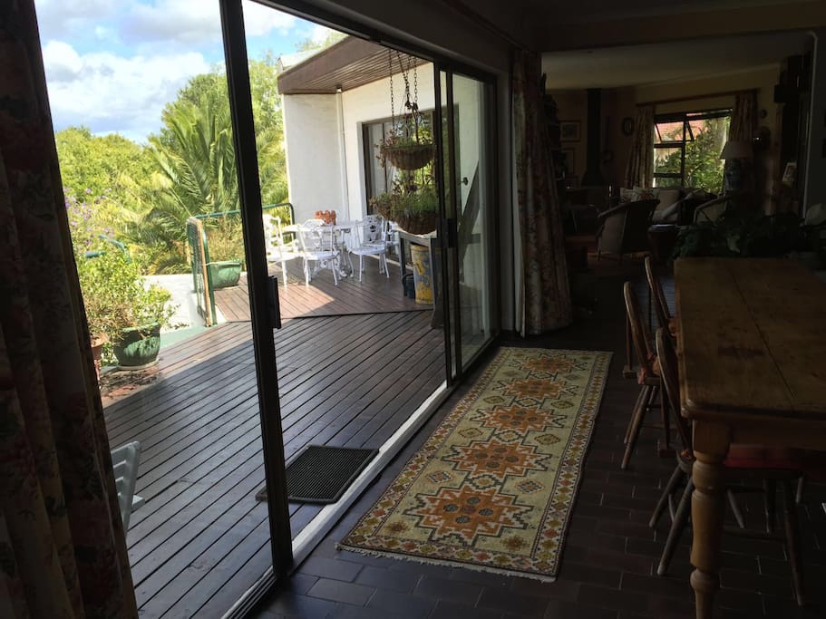 An open planning living area with Long dinner table 2 lounges and large deck which wraps around the front of the house.
