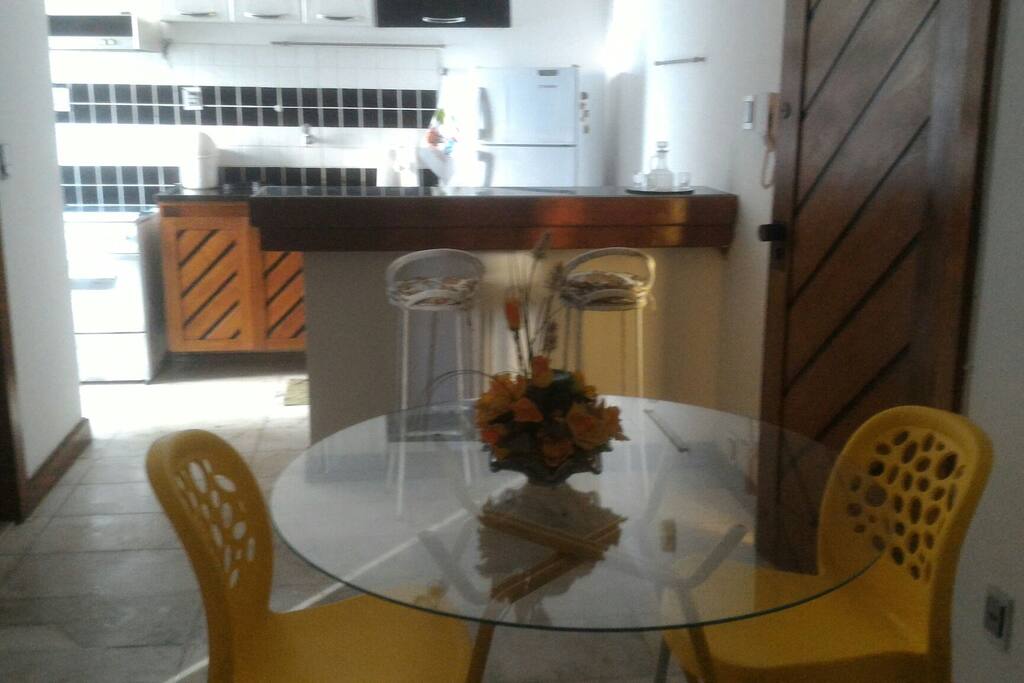 cozinha americana, com geladeira, balcão para pequenas refeições, bancos, fogão e filtro para garrafão de água