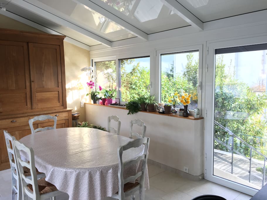 Veranda ouverte sur la cuisine et sur la terrasse C'est une grande pièce très lumineuse avec une table (5 rallonges) pour des repas entre amis ou en famille. C'est aussi un endroit pour se reposer face au jardin dans les fauteuils.