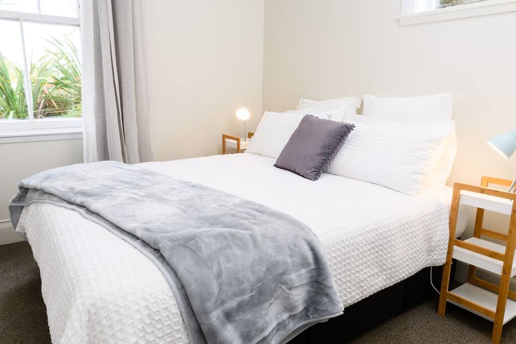 Queen bed in restful decor looking out to garden.