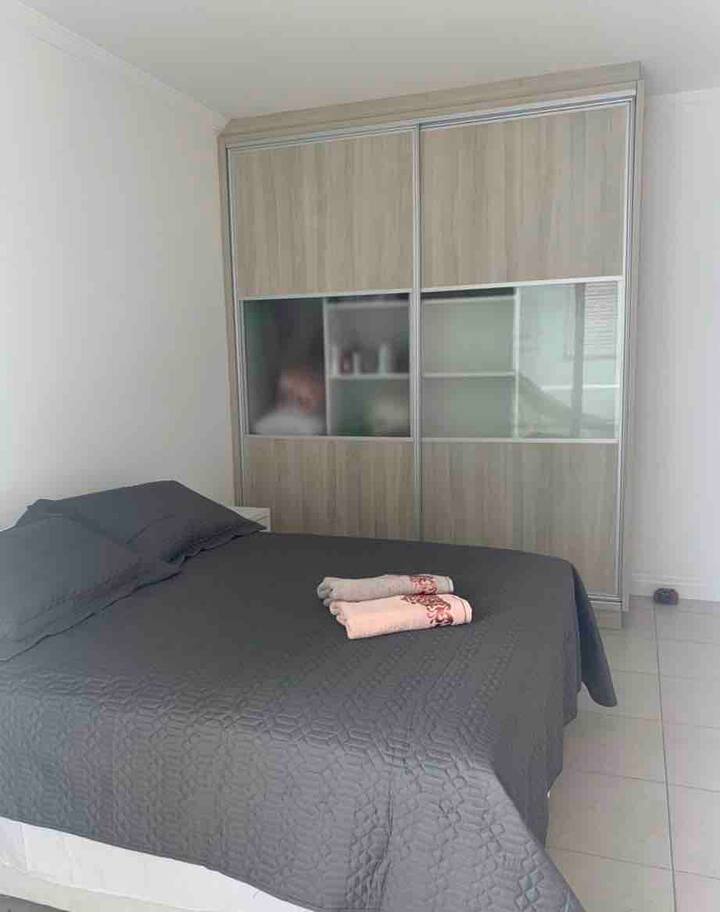 Suíte com cama queen, armário e ar condicionado.