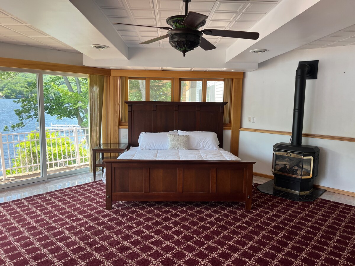 Spálňa s manželskou posteľou v osemuholníckej izbe s krásnym výhľadom na jazero. Plynový krb a televízor. 