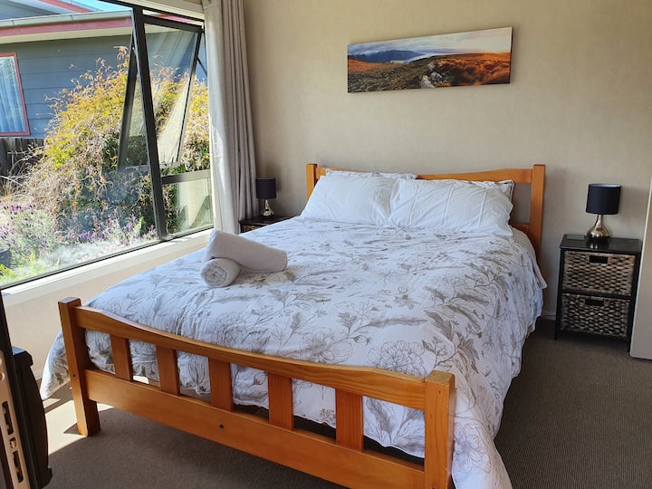 غرفة النوم الرئيسية مشرقة ومشمسة مع باب منزلق يفتح  على السطح.