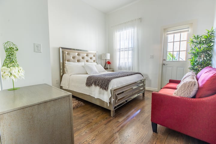 (Master Bedroom) Queen Size Bed with Private Backyard Balcony. Bedroom has a Wireless & USB Phone Charger and a Digital Safe Box. Small Sofa and Reading Lamp.