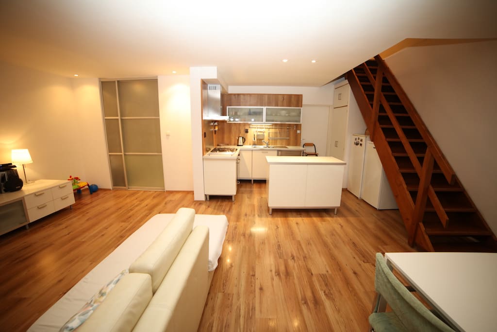 Open plan kitchen/dining/living room, with wooden staircase leading up to the top floor’s rooftop section containing two adjacent rooms with ensuite bathroom.