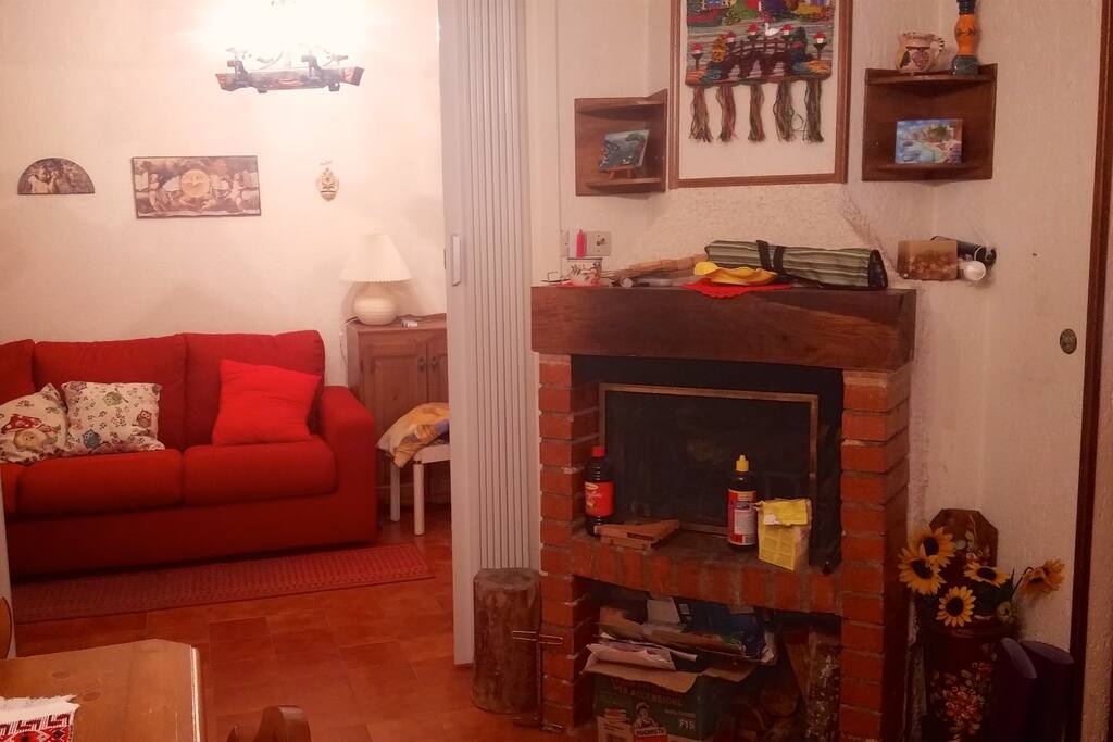 Il camino con, sullo sfondo, la camera da letto con il divano apribile.