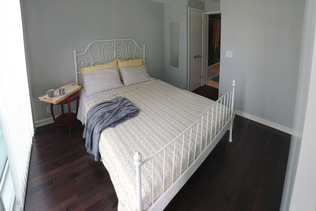 Clean and Comfortable Bedroom with Floor to Ceiling Windows and Blinds