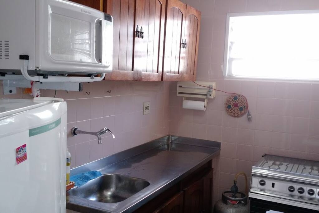 cozinha com geladeira, microondas, armários e fogão à gás