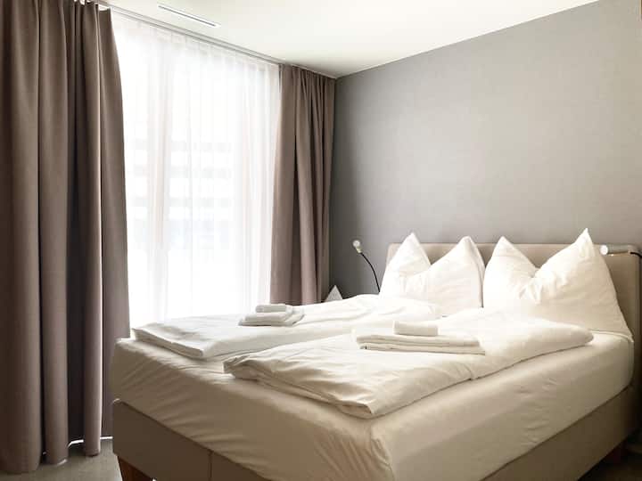 Izba s manželskou posteľou (kvalitná posteľ Jensen box spring 160 x 200 m), dvoma otvorenými prikrývkami s nočnou lampou a šatníkom s veľkorysým úložným priestorom.