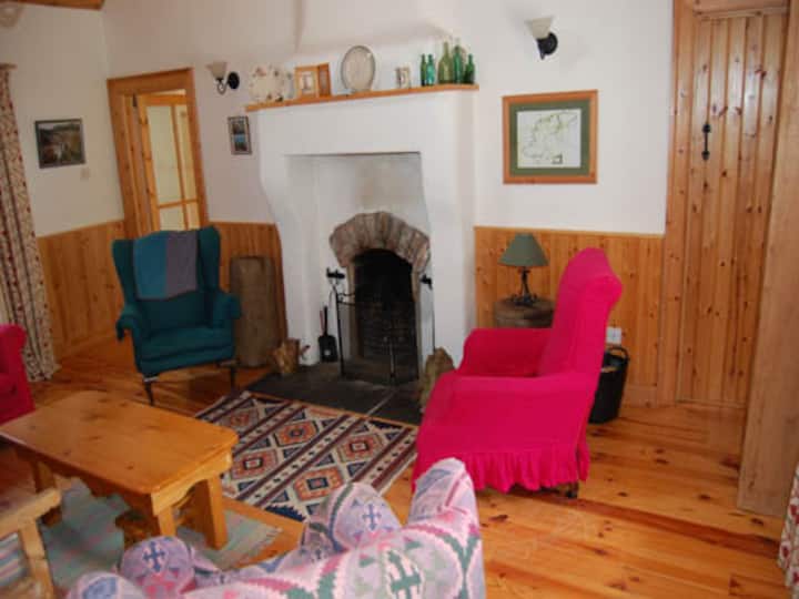 Doagh Cottage living room with open fire showing doors into king bedroom (left) and bathroom (right)